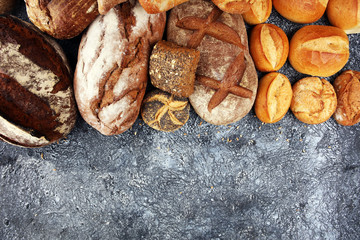 Different kinds of bread and bread rolls on board from above. Kitchen or bakery poster design