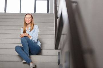 people, business and education concept - happy smiling woman or student sitting on stairs