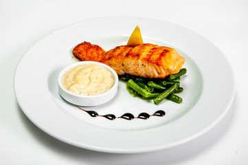 fried fish on a plate with herbs sauce and lemon