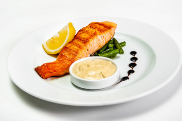 fried fish on a plate with herbs sauce and lemon