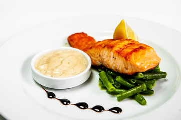 fried fish on a plate with herbs sauce and lemon