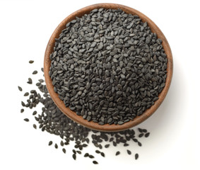 dried black sesame seeds in the wooden plate, isolated on white