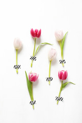 Styled stock photo. Feminine Easter, spring composition with pink tulips taped on white background. Floral pattern. Flat lay, top view. Vertical picture for blog.