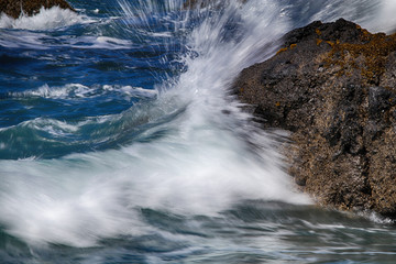 Sea water sprays a coastal rock in Oregon