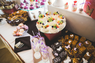 Delicious and tasty dessert table with cupcakes shots at reception closeup