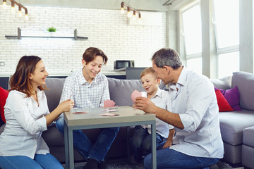 The family plays board games gaily while sitting at the table inside the room.