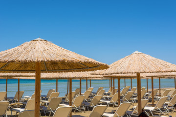Umbrellas and sunbeds on beach in summer. Naxos island. Cyclades, Greece.
