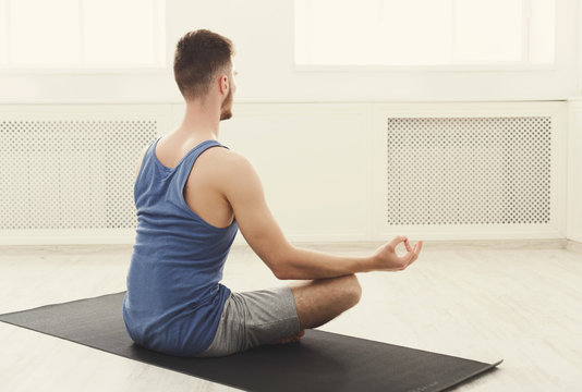 Man training yoga in lotus pose, copy space