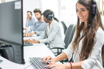 Beautiful smiling customer support agent operator woman with headset working on desktop computer in...