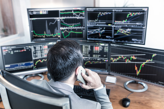 Over The Shoulder View Of Computer Screens Ful Of Charts And Data Analyses And Stock Broker Trading Online.