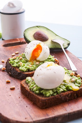 breakfast bruschetta with avocado and spinach and poached egg. with a cup of coffee