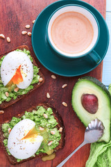 breakfast bruschetta with avocado and spinach and poached egg. with a cup of coffee