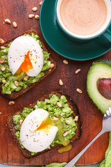 breakfast bruschetta with avocado and spinach and poached egg. with a cup of coffee