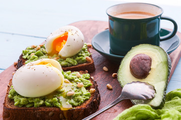 breakfast bruschetta with avocado and spinach and poached egg. with a cup of coffee