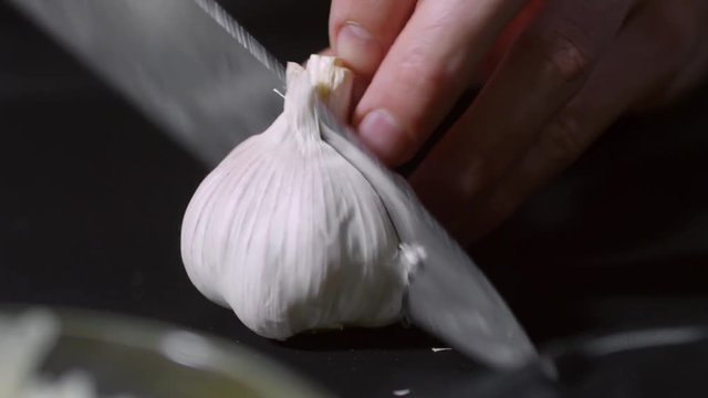 Close up of unrecognizable man cutting fresh garlic