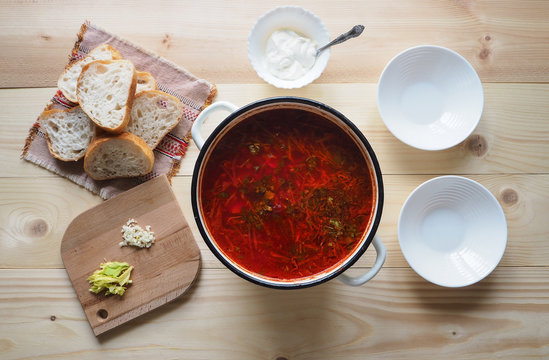 A large pot with a red borscht on a rough wooden table.