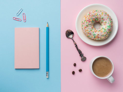 Flat lay Coffee Cup Donut Notepad Pencil Vanilla on a Pink Blue background