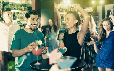 adult smiling male with female are talking and drinking cocktail