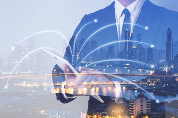 double exposure of businessmen using tablet with city night and network connection concept.