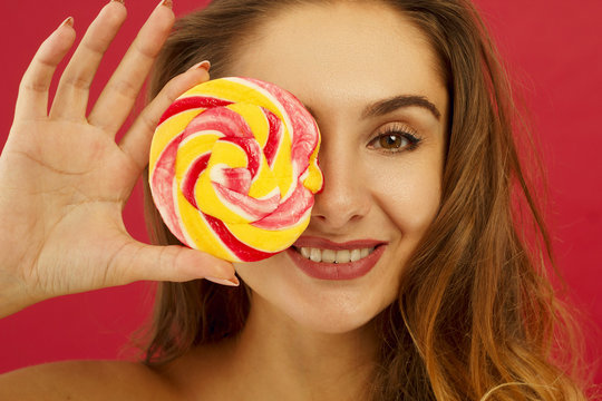 Portrait of a pretty girl holding sweet candy over red background