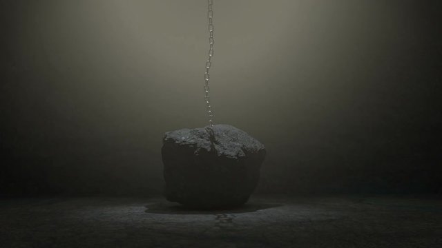 Metal chain attached to a large boulder or rock is lifted up and pull strongly against the confinement, eventually breaking free with a small explosion.