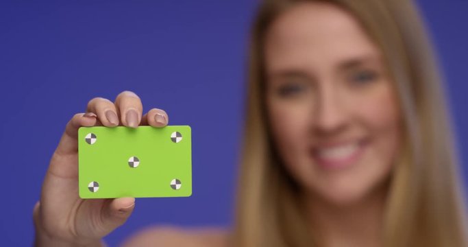 Beautiful Woman holding a blank Credit Card  into the Camera with focus on the Card