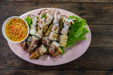 grilled squid and seafood sauce on wooden table