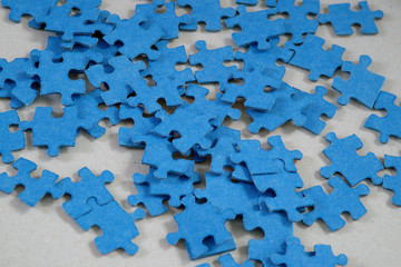 Blue jigsaw puzzle pieces on gray background in perspective