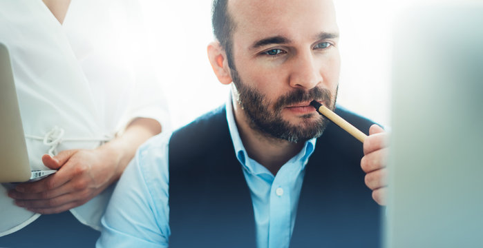 Bearded young businessman working on modern office. Consultant man thinking looking in monitor computer. Manager coworking on workplace, discussio startup project concept in studio with colleague