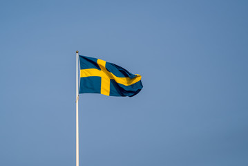 the swedish flag on a white pole in the middle of the town of Fi