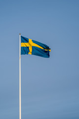 the swedish flag on a white pole in the middle of the town of Fi