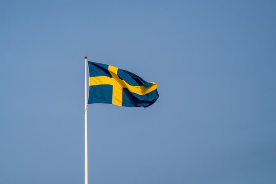the swedish flag on a white pole in the middle of the town of Fi