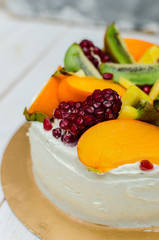 Exotic cake. Sponge cake with white cream and a lot of fruit (kiwi, pomegranate, persimmon, mango)
