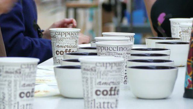 People with coffee spoons tasting coffee.