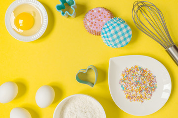 concept of the Easter bakery, various products for home baking, sugar, eggs and flour, coconut munt, top view, empty space for text on a yellow background in the style of pop art mocap layout