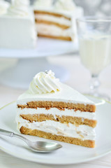 Triangular piece of tender biscuit cake in white cream with cream peaks and silver beads