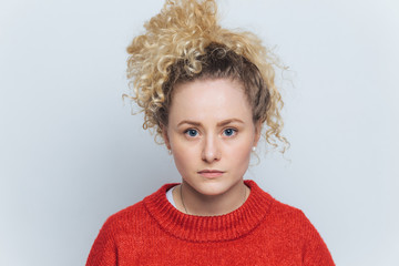 Headshot of serious pleased beautiful woman with healthy skin, blue eyes and curly hair, dressed casually, isolated over white studio background. People, facial expressions and beauty concept