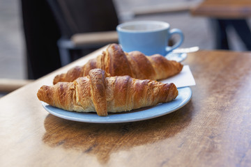 two fresh croissants on a plate closeup as background