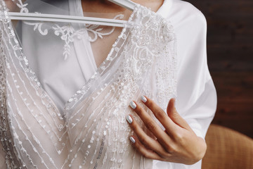 Bride.Preparations.Wedding.Manicure. Bride touch beads on your white wedding dress by hand with pearl nails.