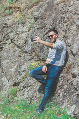 Naklejka premium Beautiful young man using smartphone in the nature