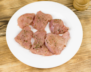 Raw chicken fillet sprinkled with spices on a wooden background. Preparation for cooking.