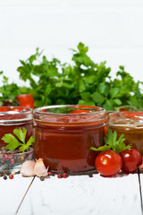 assortment of tomato sauces and ingredients on white wooden background, vertical