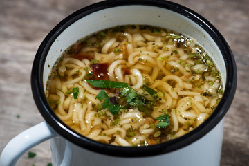 hot chicken soup with noodles in a mug, closeup