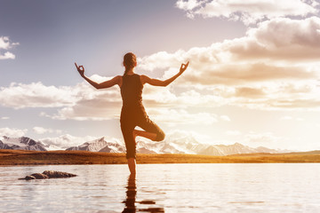 Slim girl practicing yoga in mountain lake