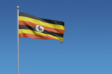 Flag of Uganda in front of a clear blue sky