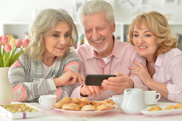 happy senior people with smartphone drinking tea