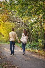 Obraz premium Young romantic couple in love walking in the autumn park holding hands. Lifestyle concept