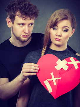 Sad couple holds broken heart.
