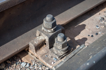 Detail of rusty screws and nut on old railroad track. Concrete tie with rusty nuts and bolts