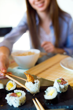 Beautiful young woman eating japanese food at home.